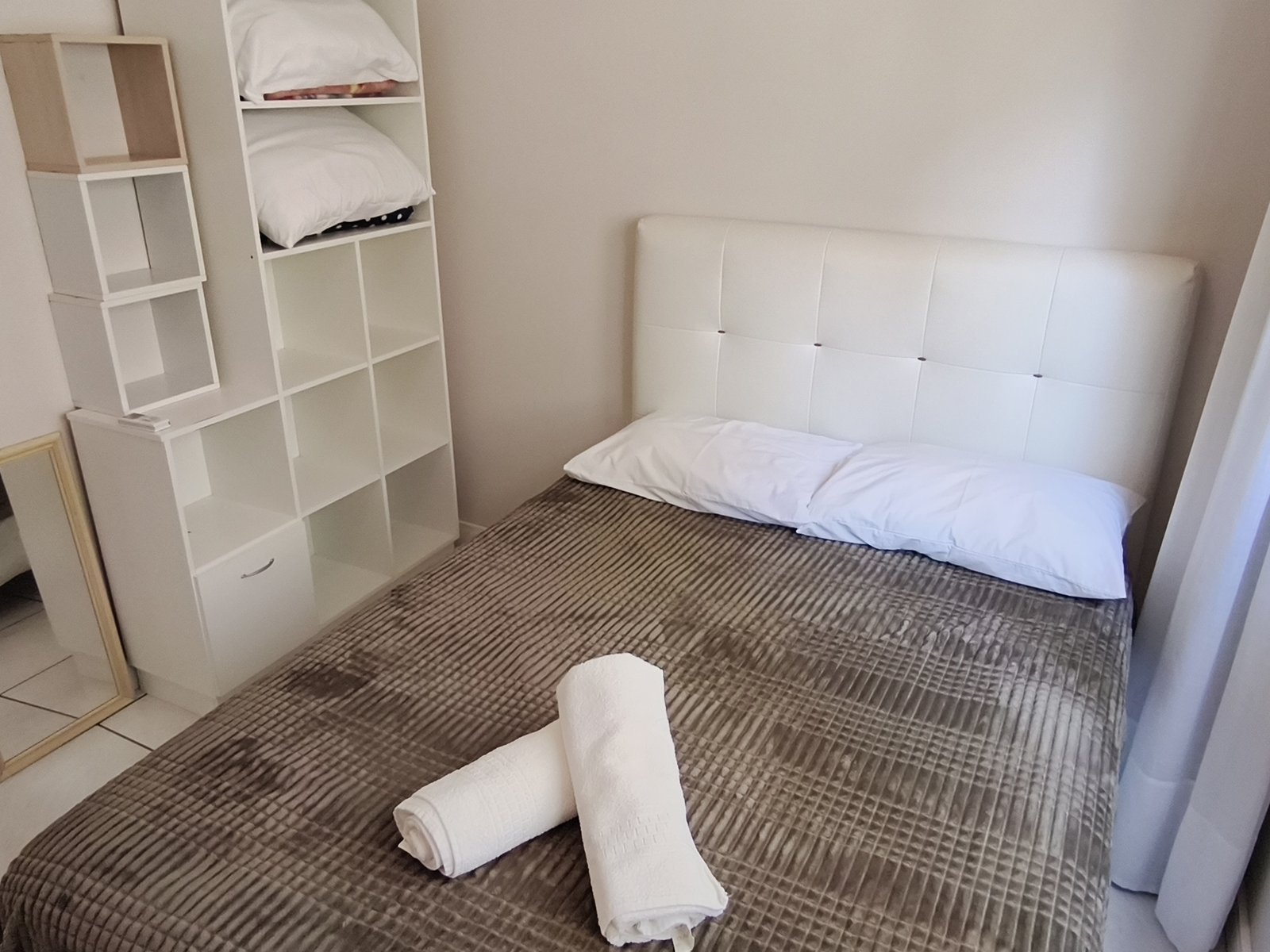 Quarto com cama de casal, cabeceira branca e nicho organizador
