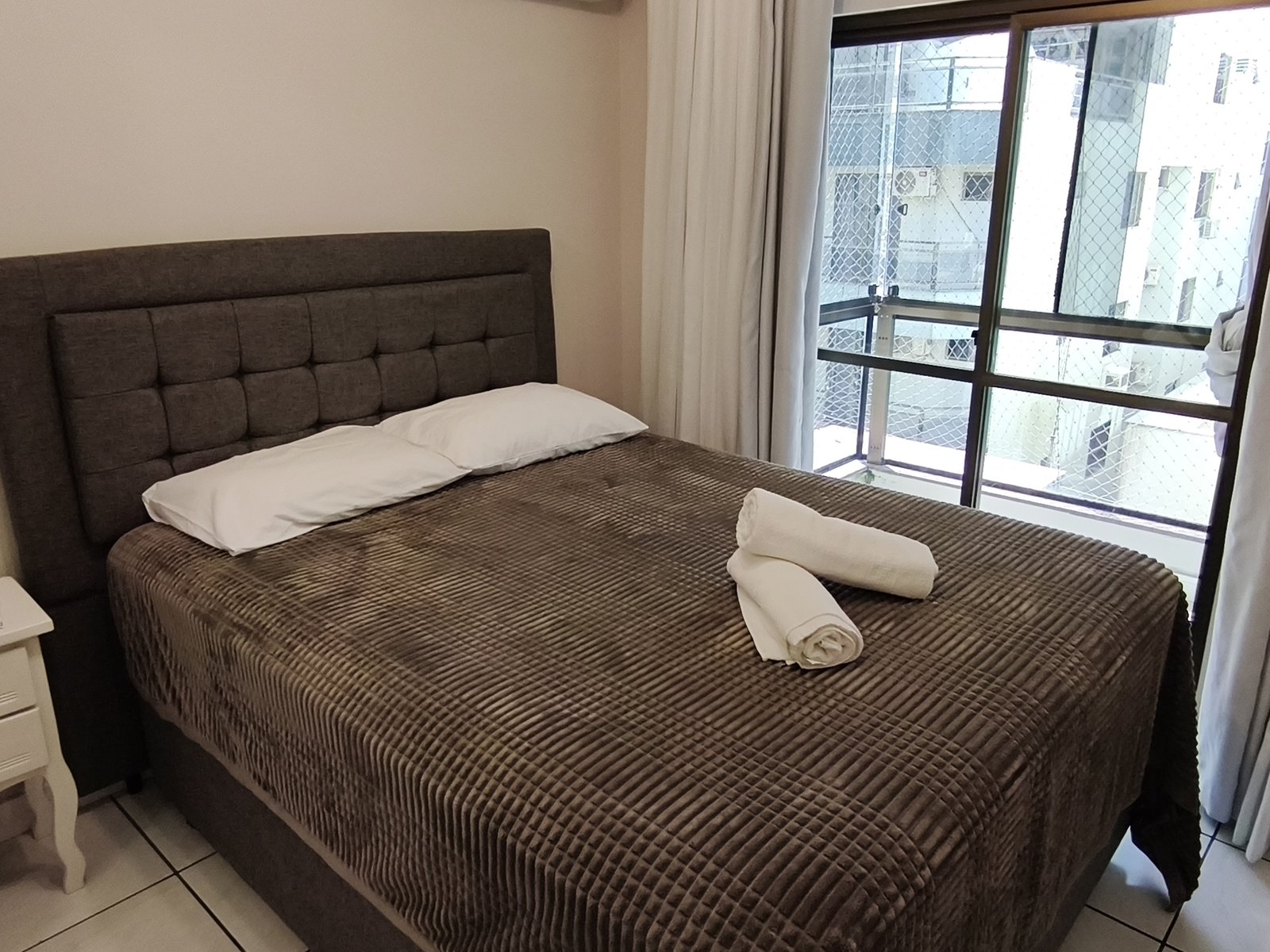 Quarto com cama de casal e cabeceira capitonê escura