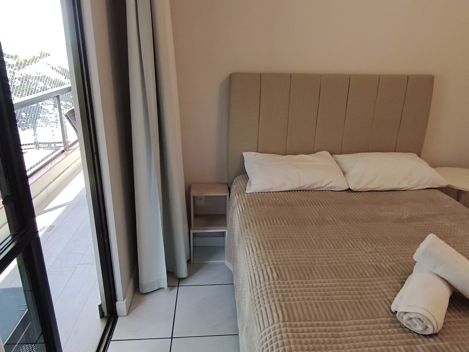 Quarto com cama de casal e saída para a sacada