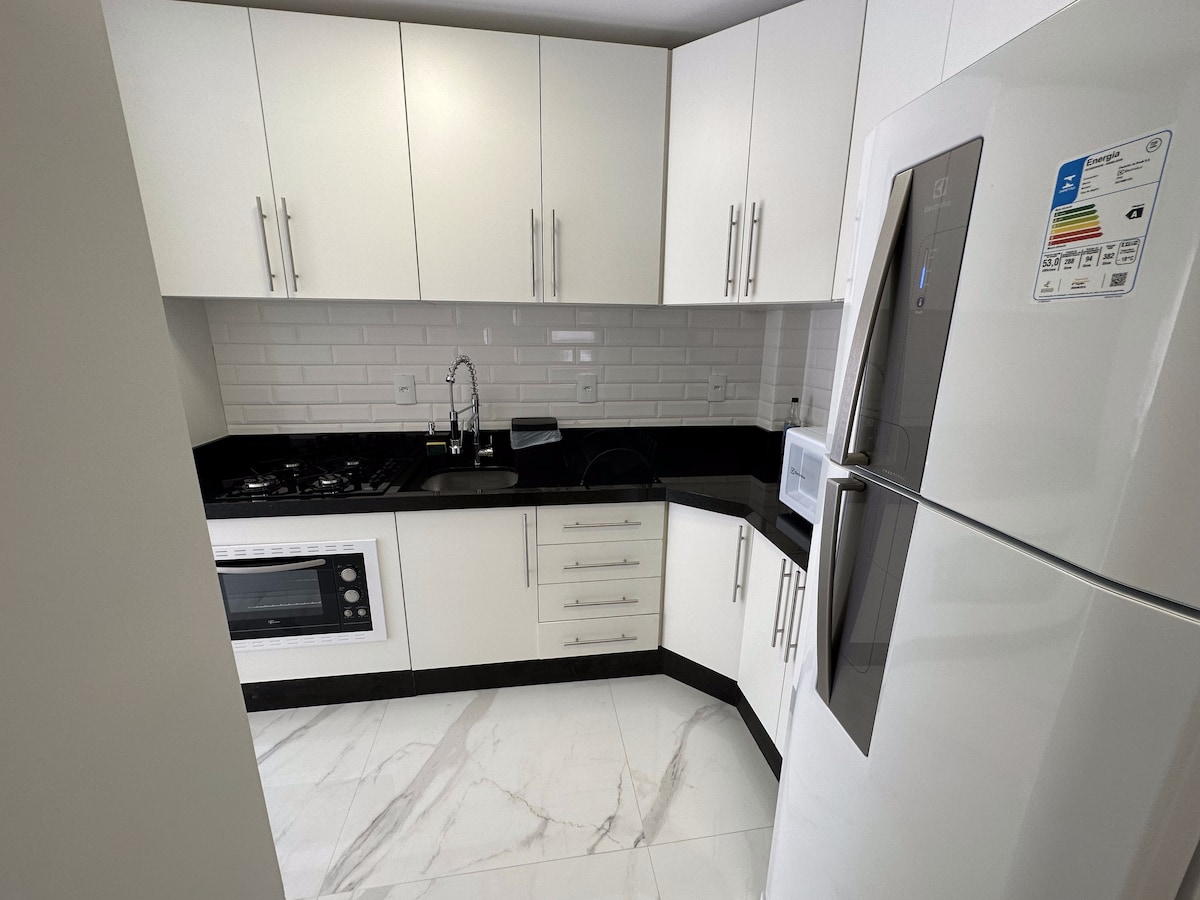 Cozinha planejada com bancada de granito preto, cooktop e forno embutido