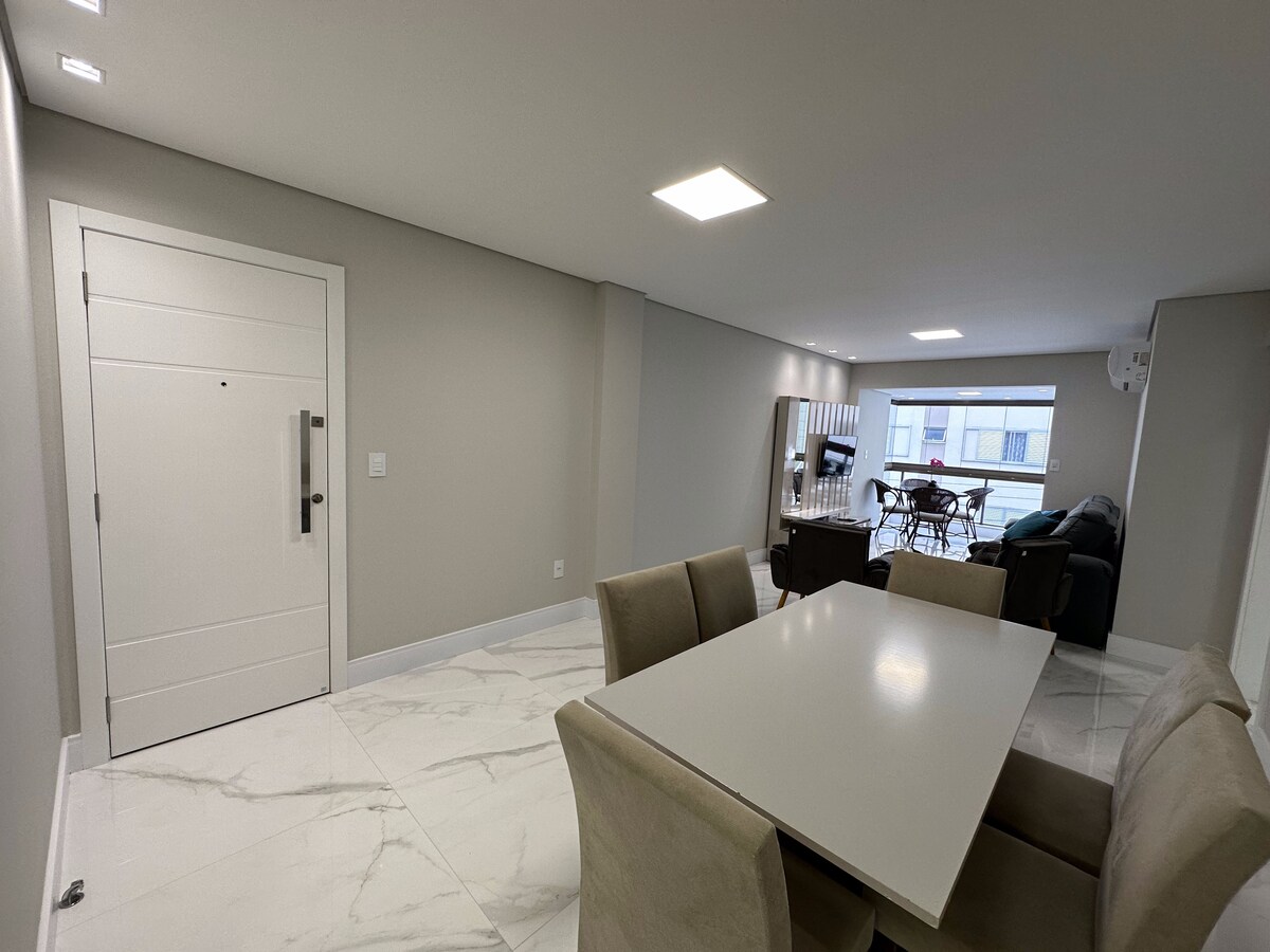Sala de jantar com mesa para seis lugares, ao lado da entrada