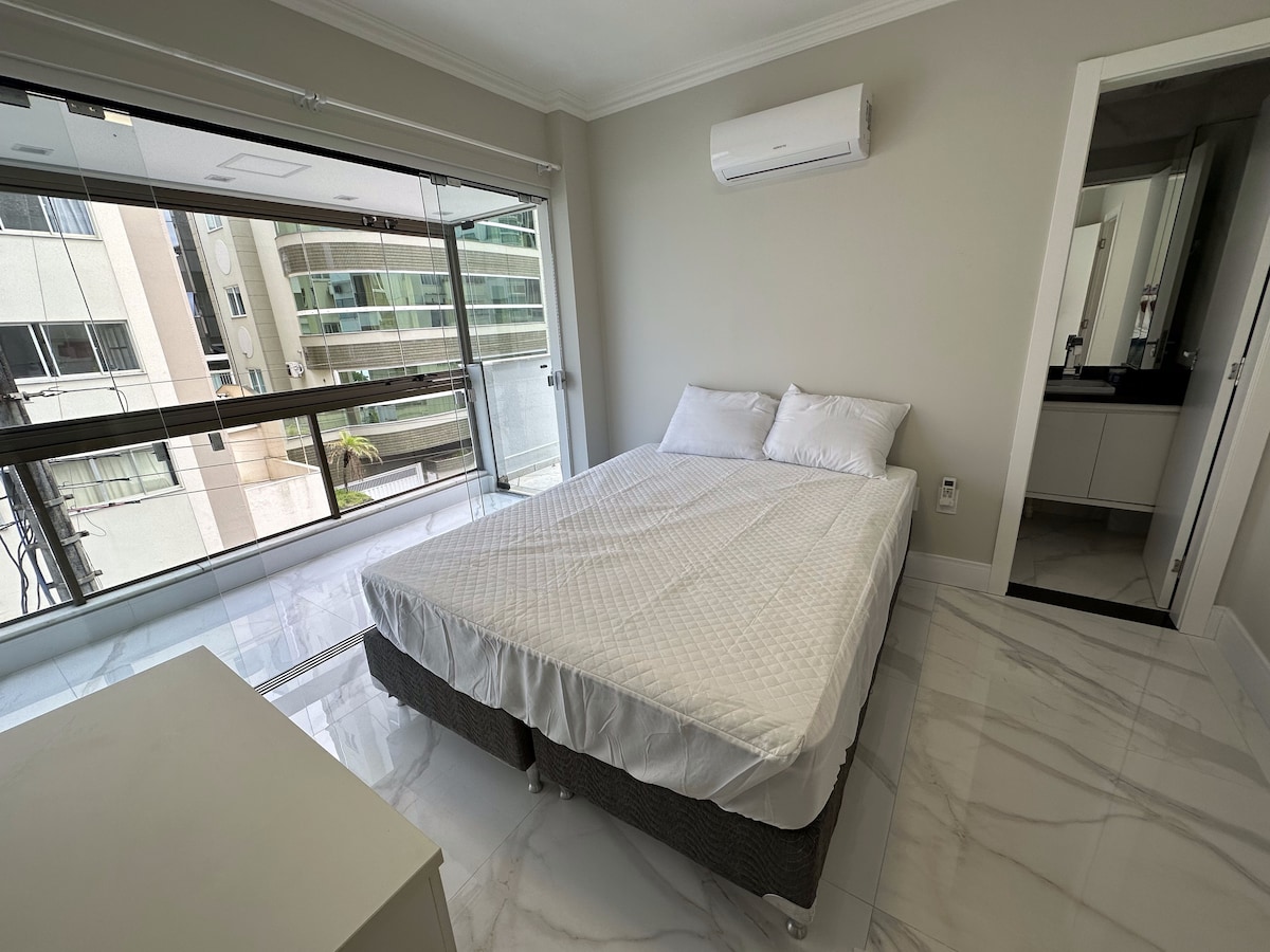 Quarto de casal com janela ampla e espelho de corpo inteiro