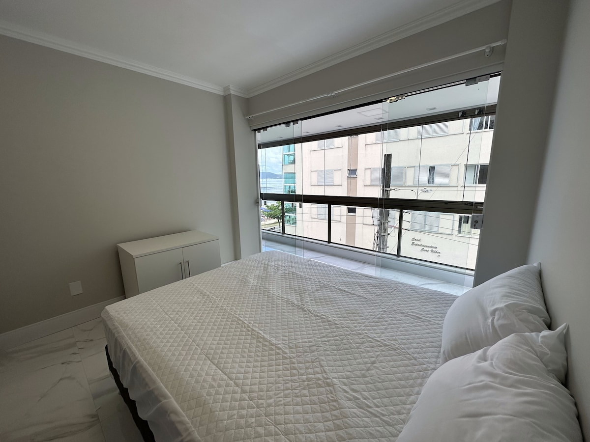 Quarto de casal com janela ampla para a rua e o mar