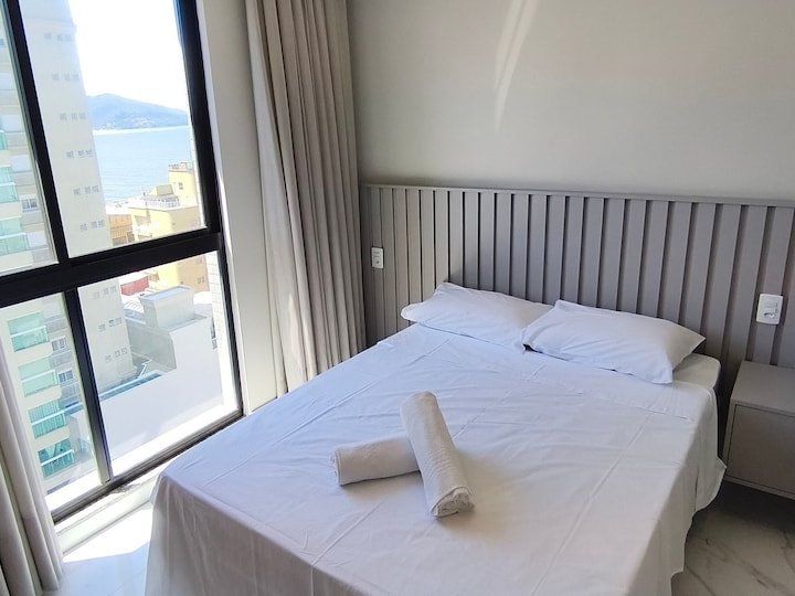 Suíte com cama de casal e janela com vista mar