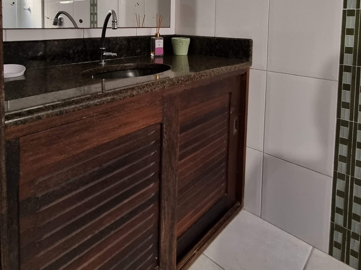 Banheiro com bancada de granito e armário de madeira