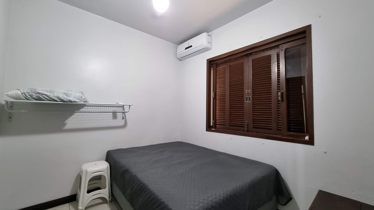 Quarto com cama queen, persianas de madeira e ar-condicionado