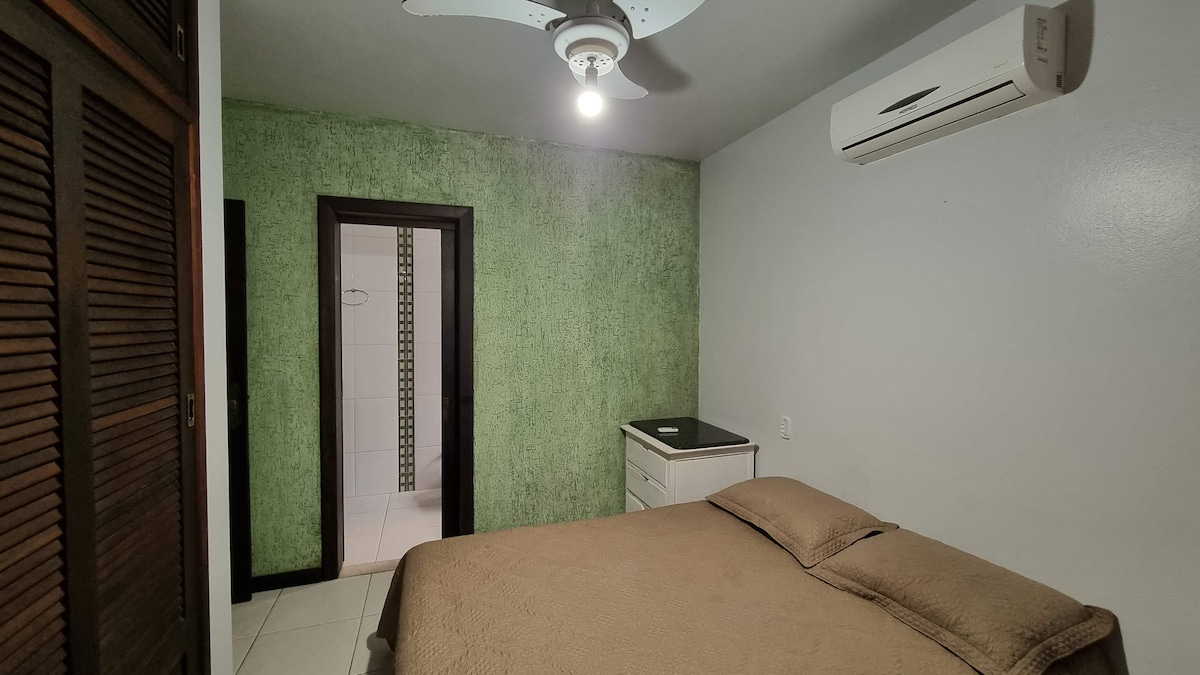 Quarto com parede verde e cama de casal