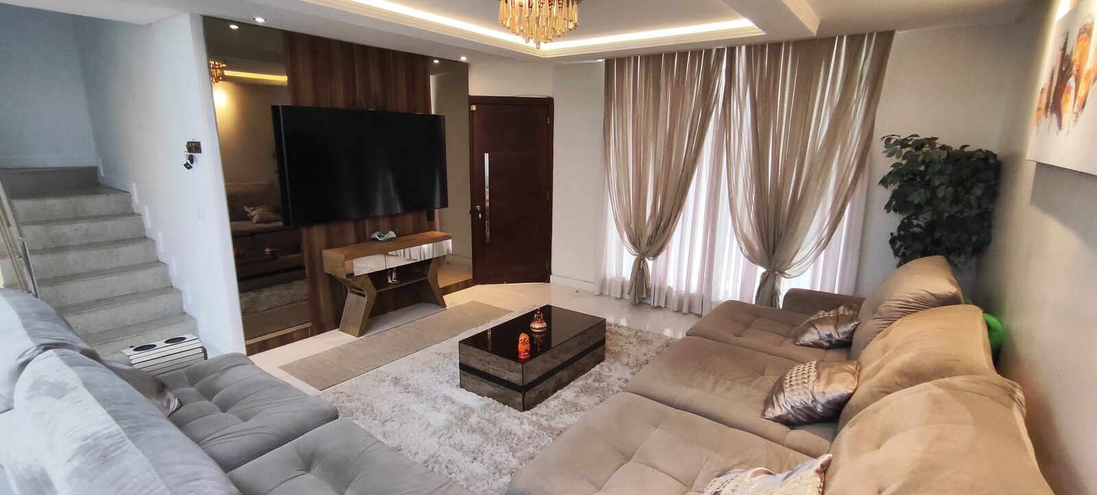 Sala de estar ampla com sofás e escada