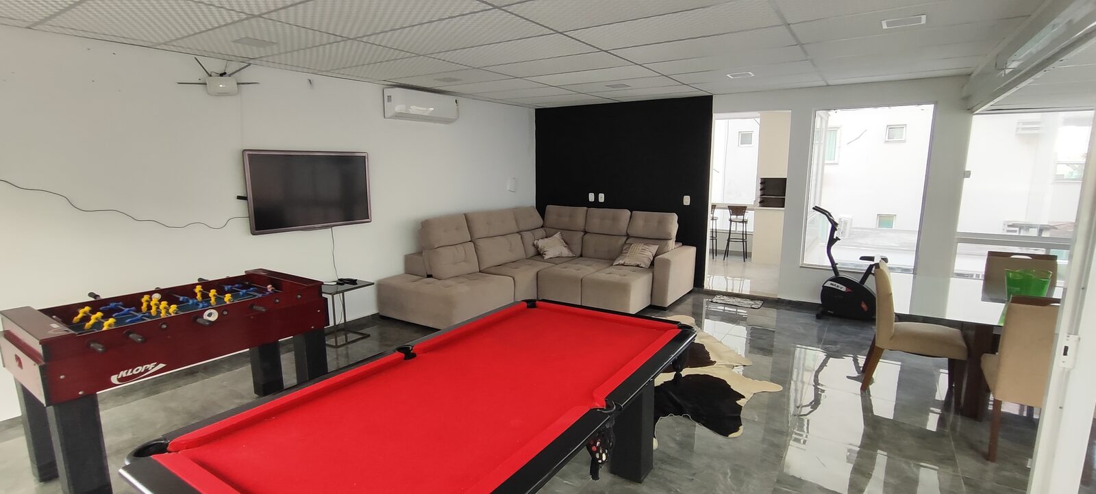 Sala de jogos com sinuca, pebolim e sofá