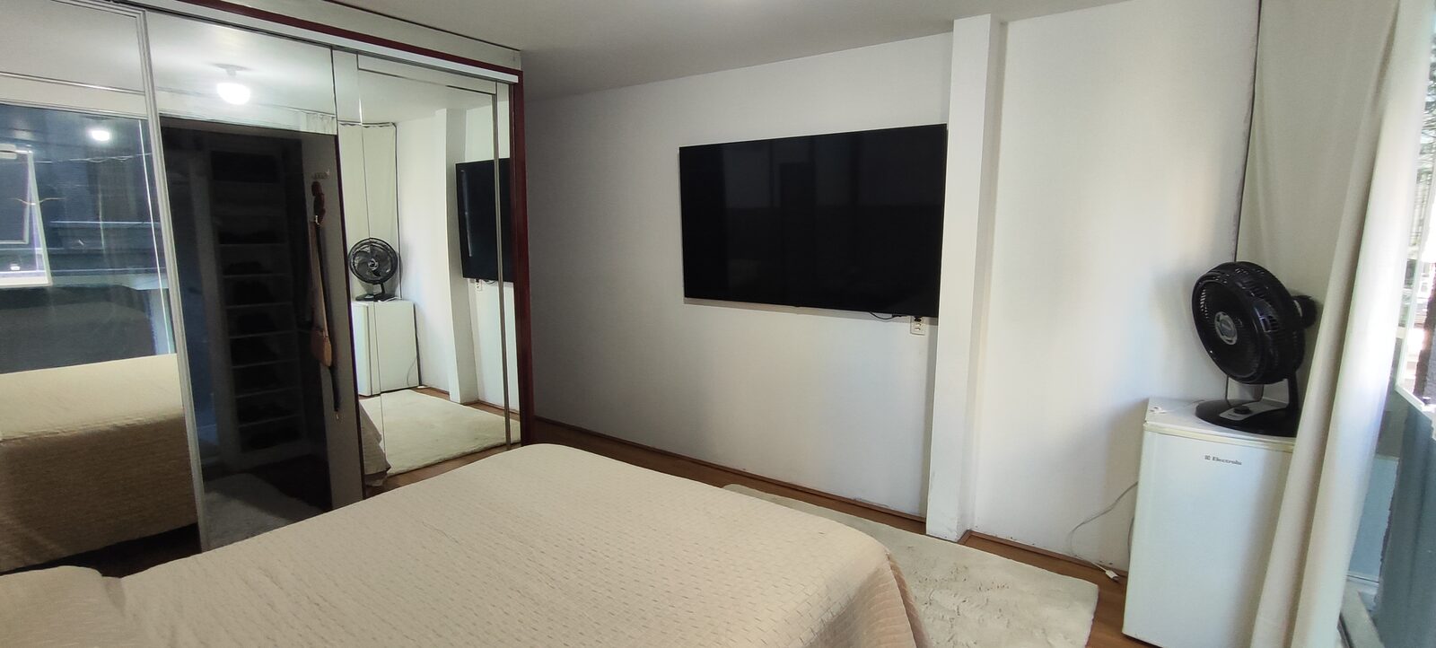Suíte com cama queen e closet espelhado