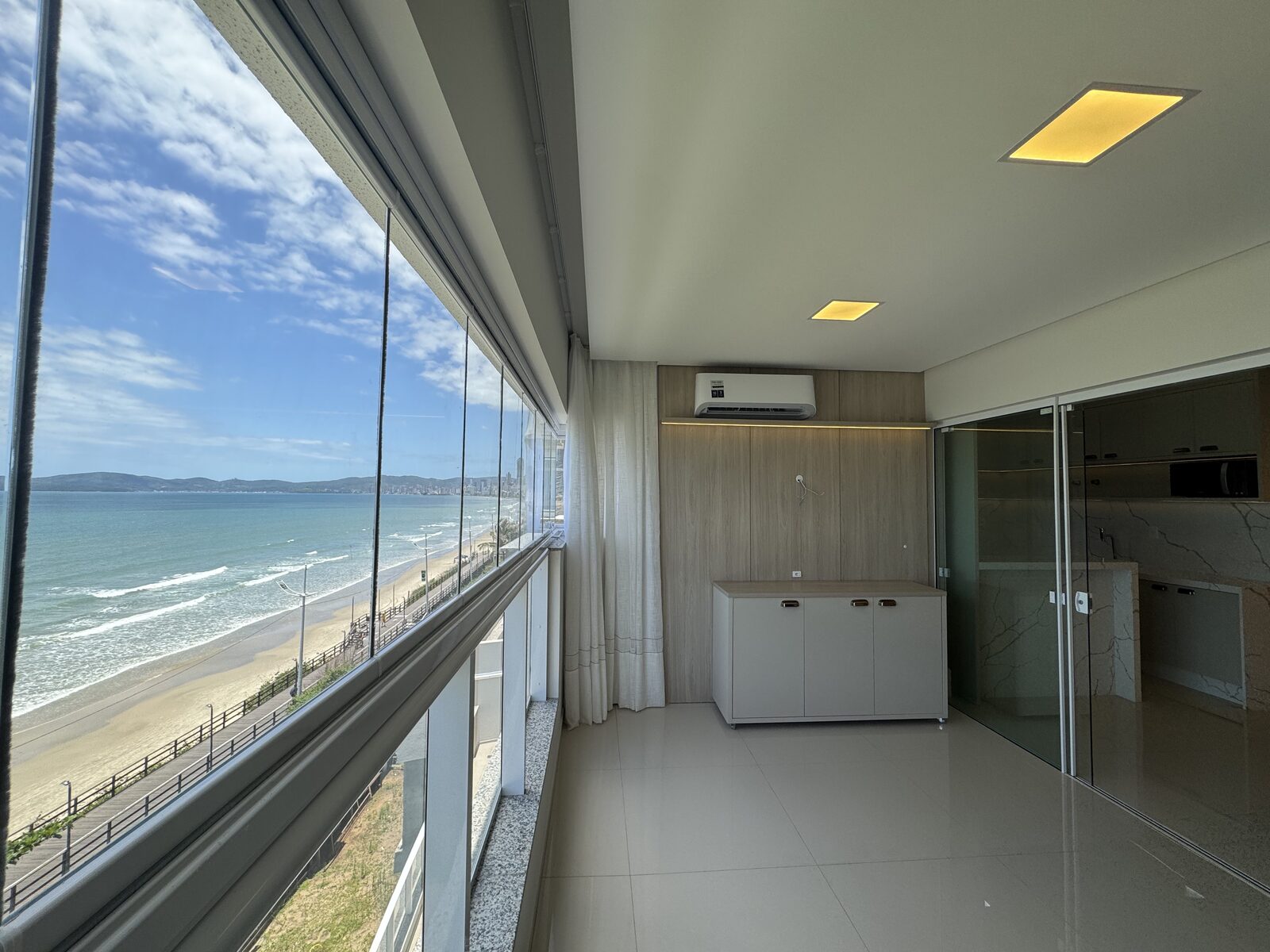 Sala integrada com vidraça do piso ao teto e vista do mar
