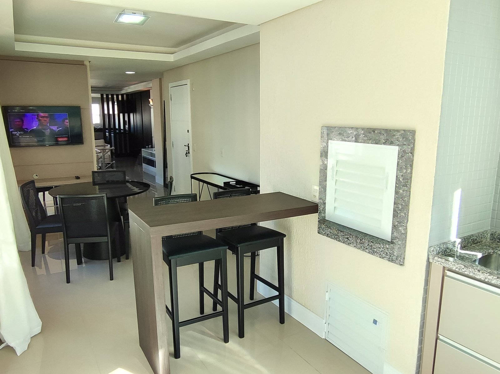 Espaço gourmet com bancada alta, banquetas e cuba
