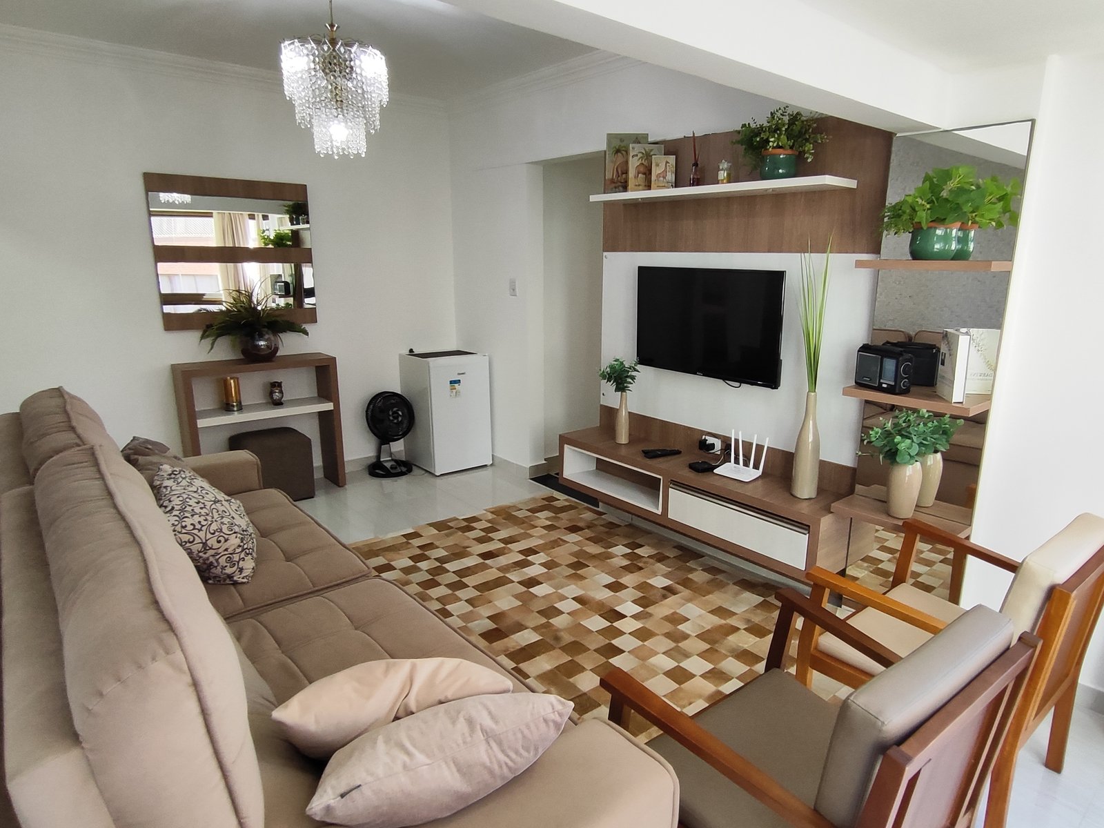 Sala de estar com sofá, TV e painel com nichos decorativos