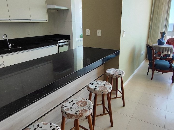 Cozinha com bancada em granito preto e banquetas