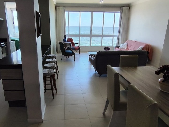 Sala integrada à cozinha, com mesa de jantar e vista mar