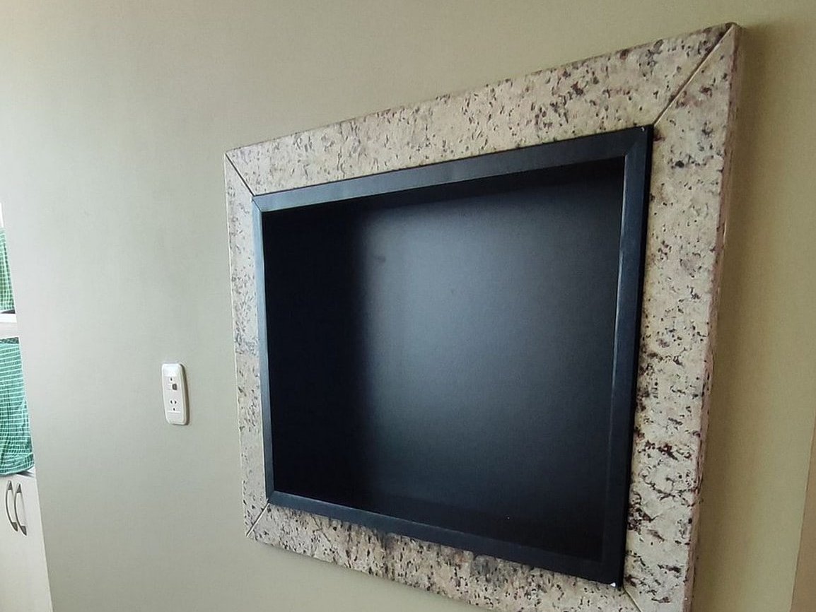 TV embutida em nicho com moldura de granito