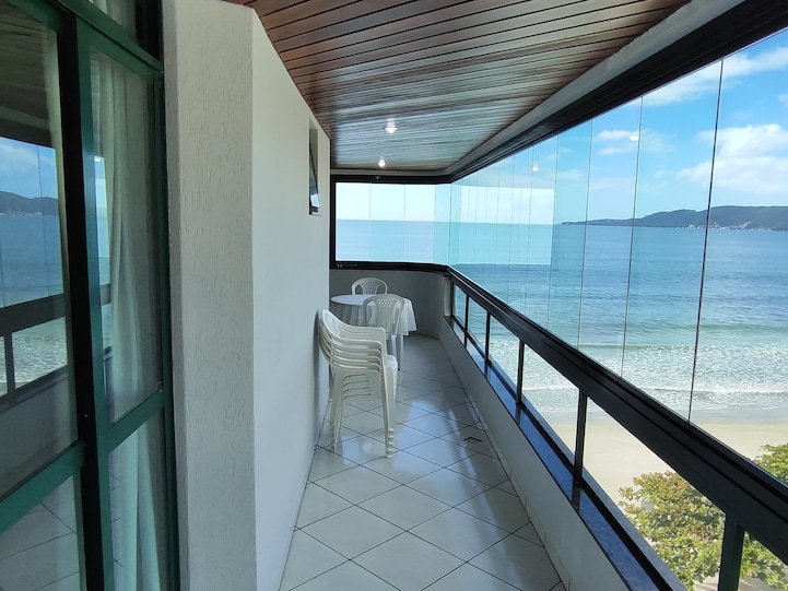 Varanda envidraçada com mesa e vista mar