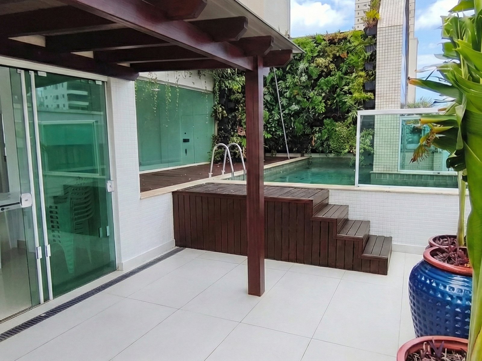 Terraço com pérgola de madeira e acesso à piscina