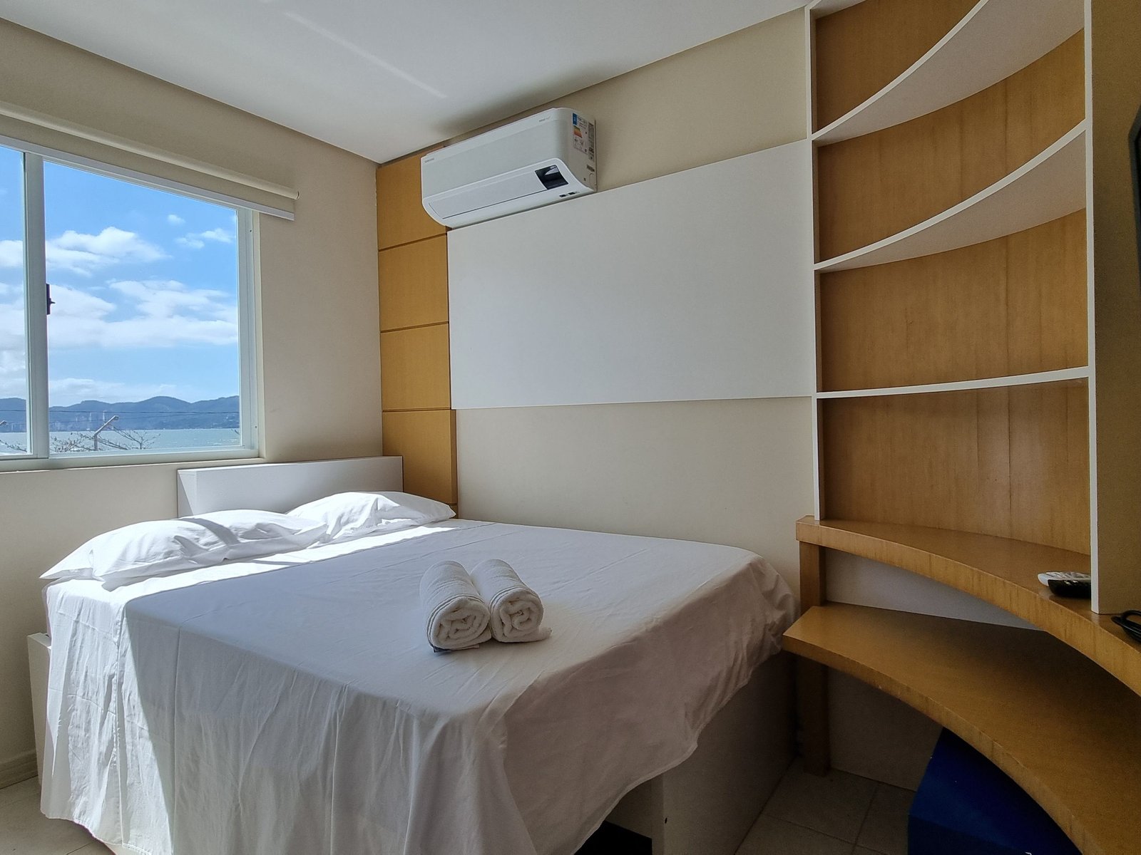 Suíte principal com cama de casal, TV smart e vista mar