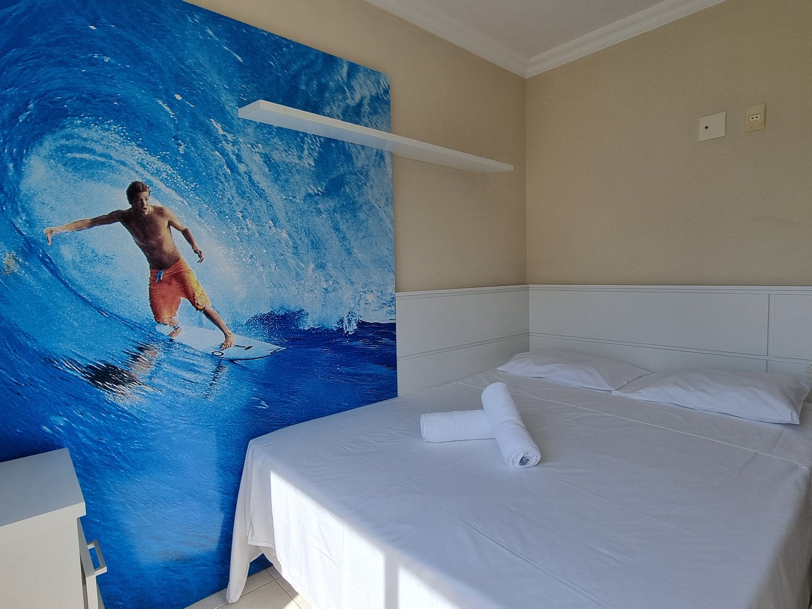 Quarto com mural de surfista e cama de casal