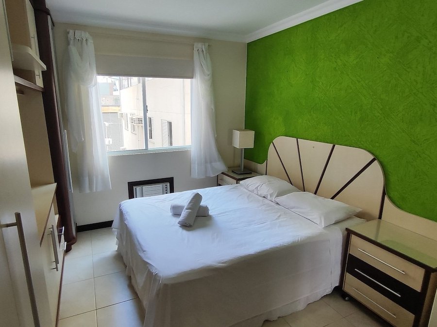 Quarto com cama de casal e parede verde
