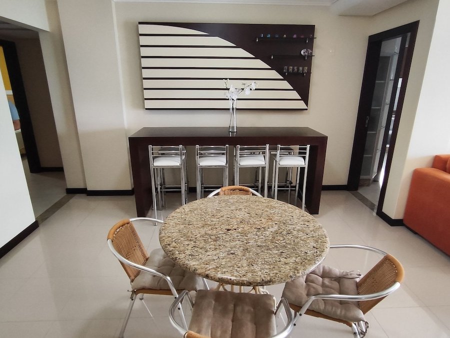 Sala de jantar com mesa de granito e bar com banquetas