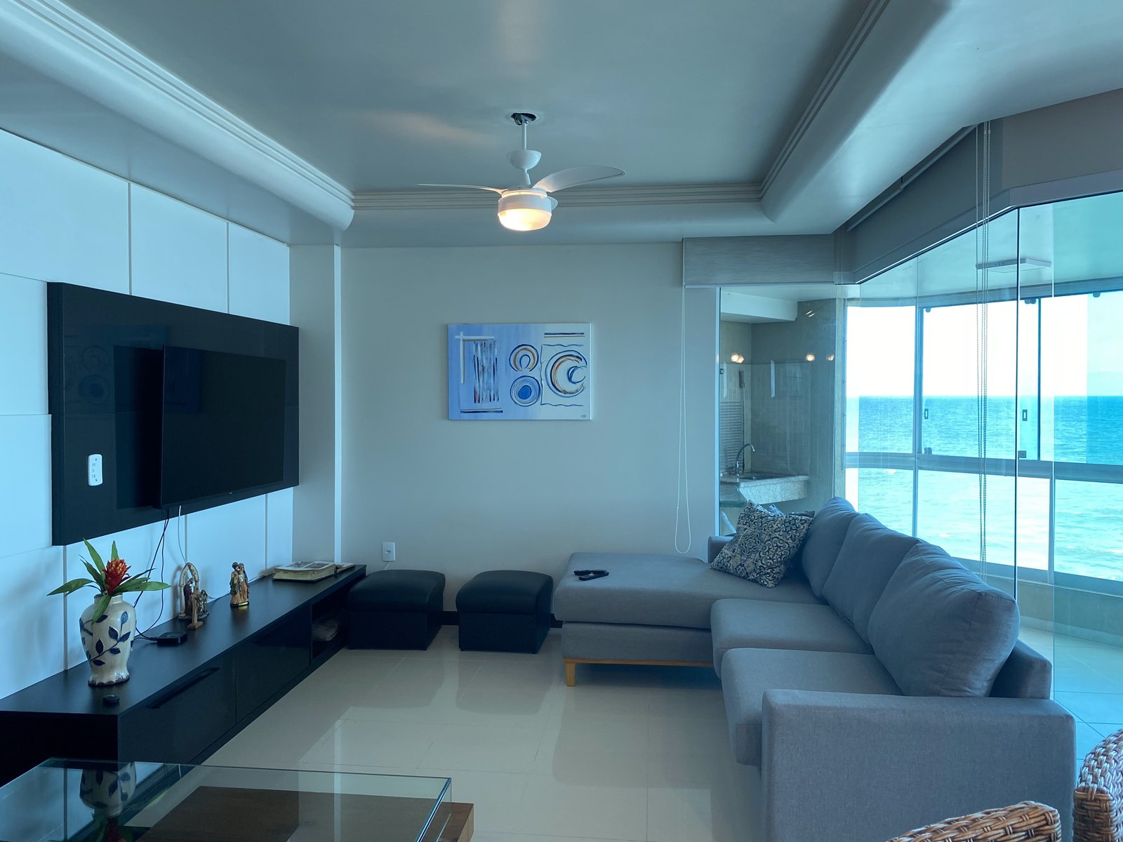 Sala de estar com TV, sofá e vista para o mar