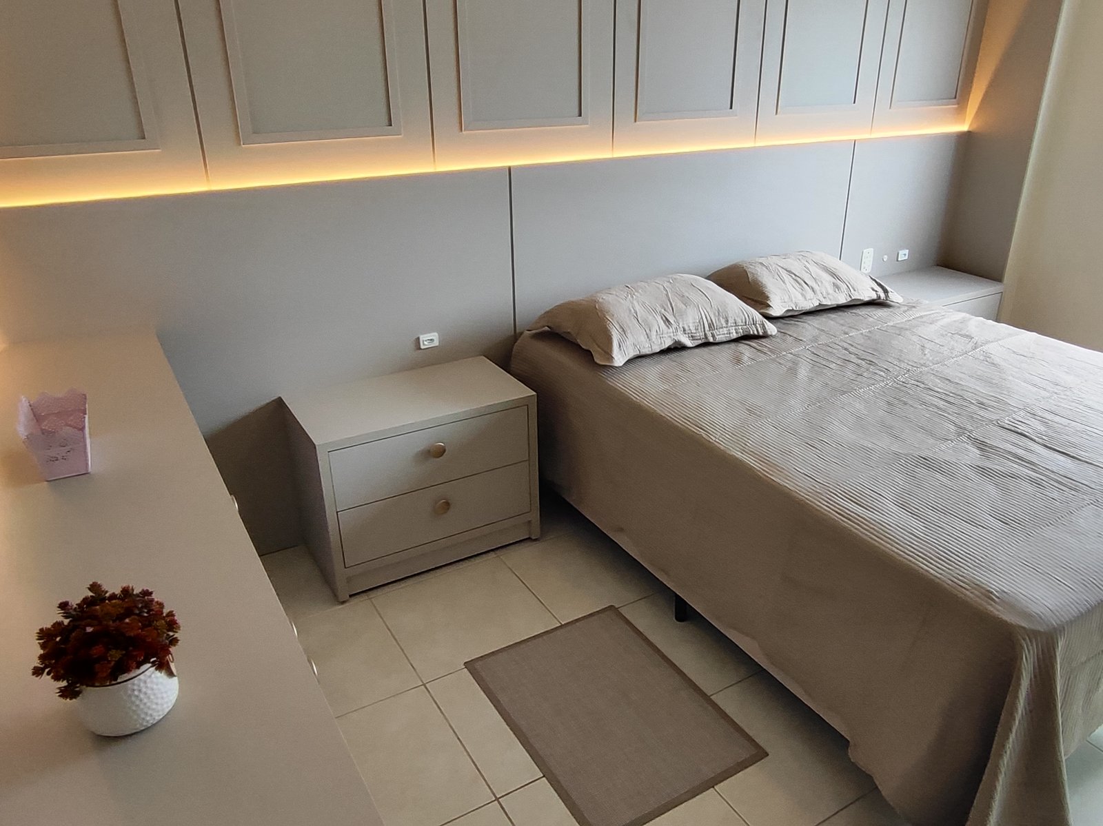 Quarto com cama de casal e iluminação em fita de LED sobre os armários