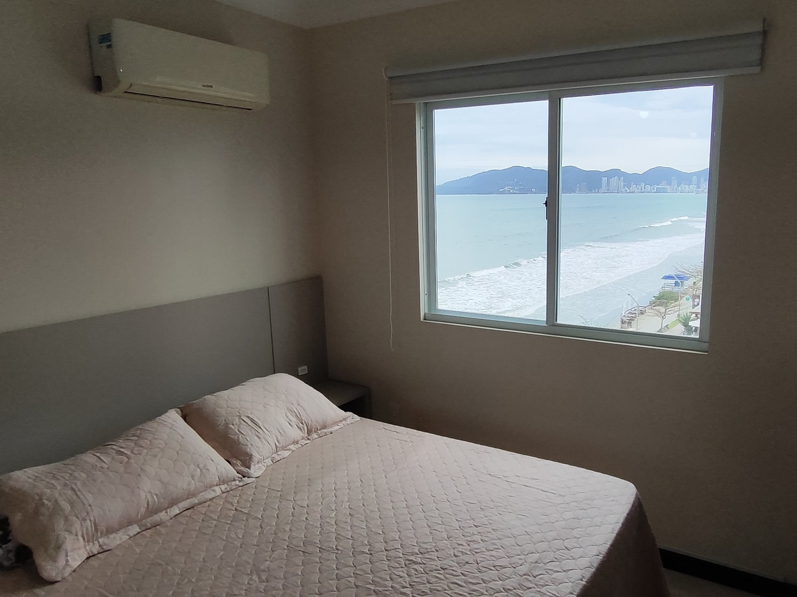 Quarto com cama de casal e janela com vista para o mar