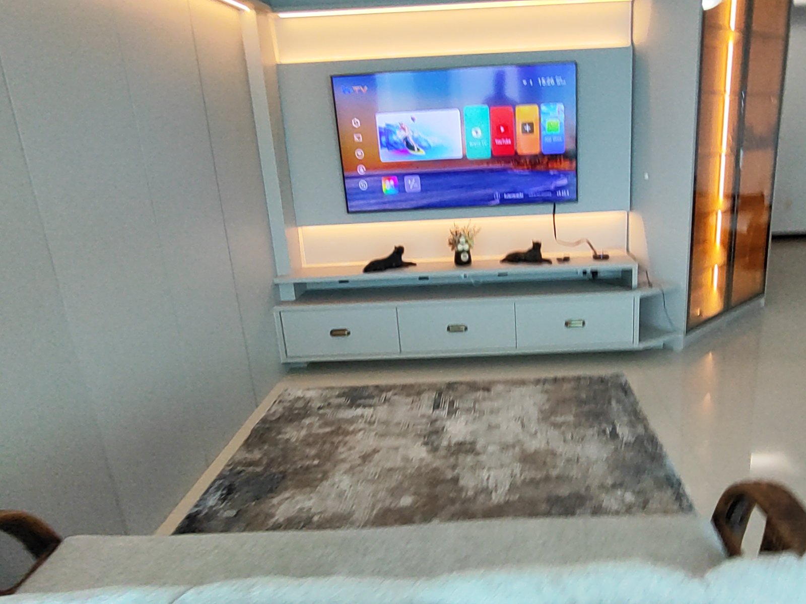 Sala de estar com TV, painel de madeira e tapete
