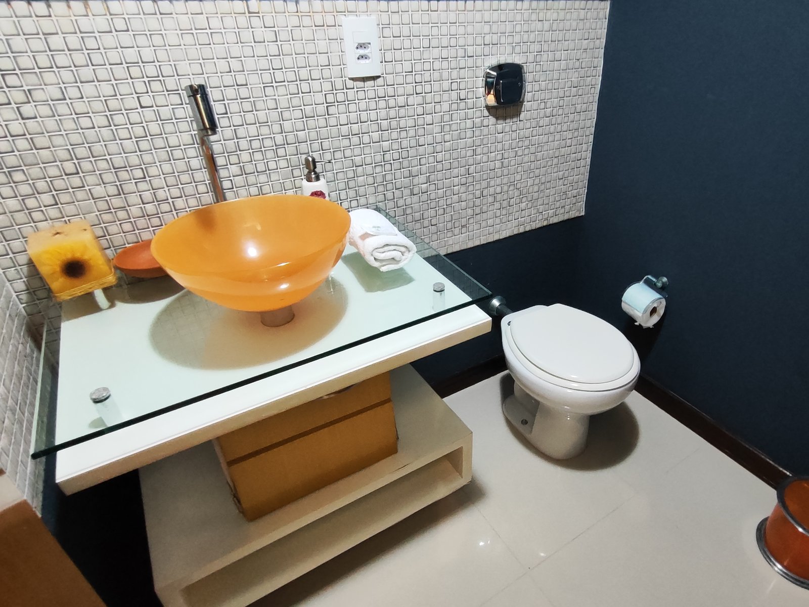Lavabo com cuba de vidro laranja sobre bancada