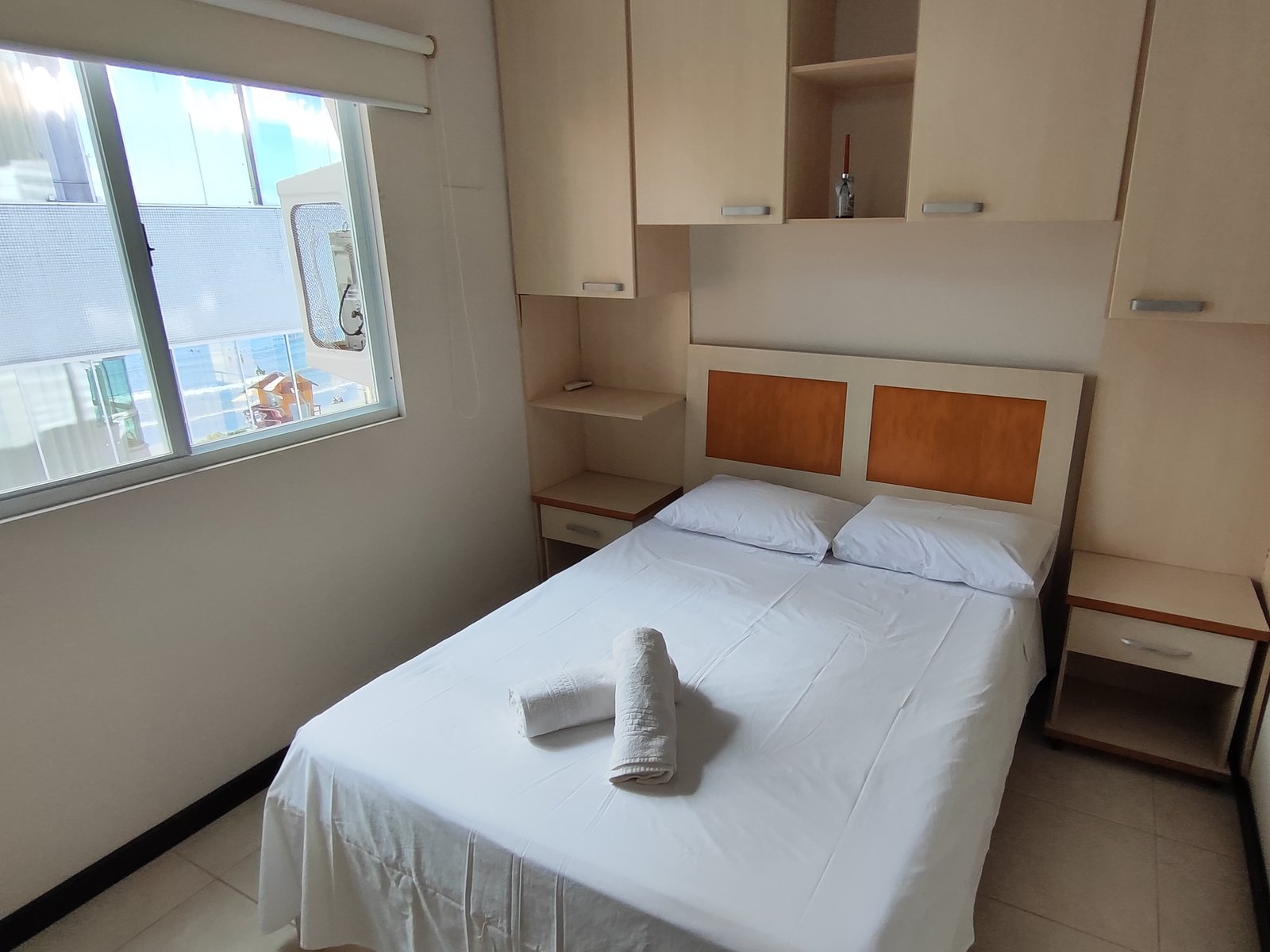 Quarto com cama de casal e armários planejados sobre a cabeceira
