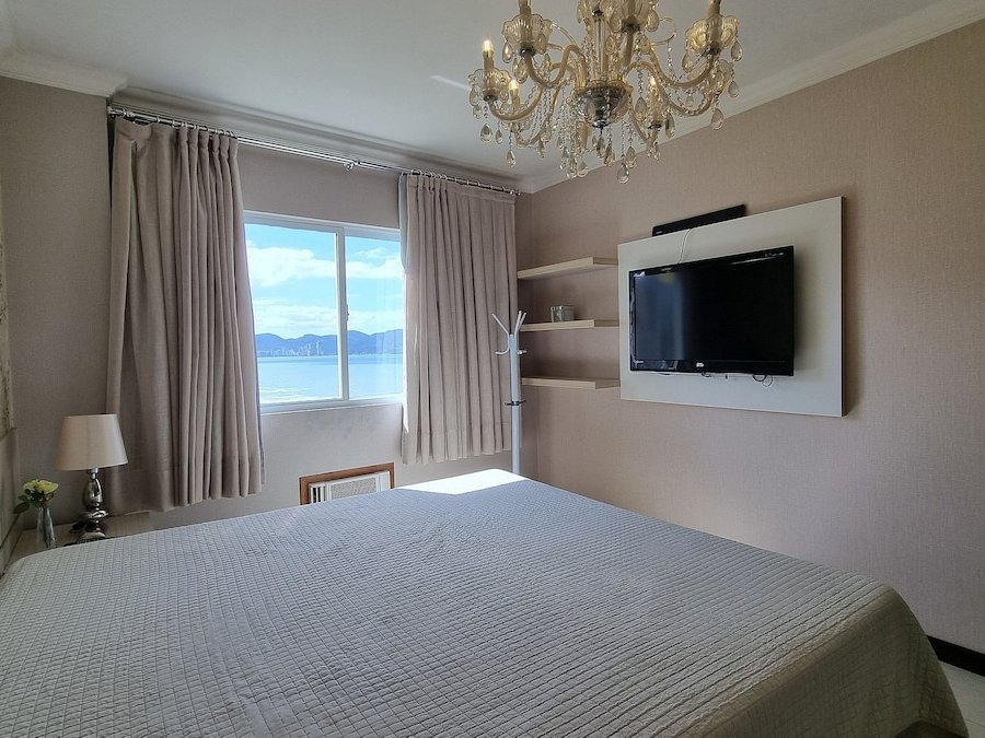 Quarto com lustre de cristal e vista mar