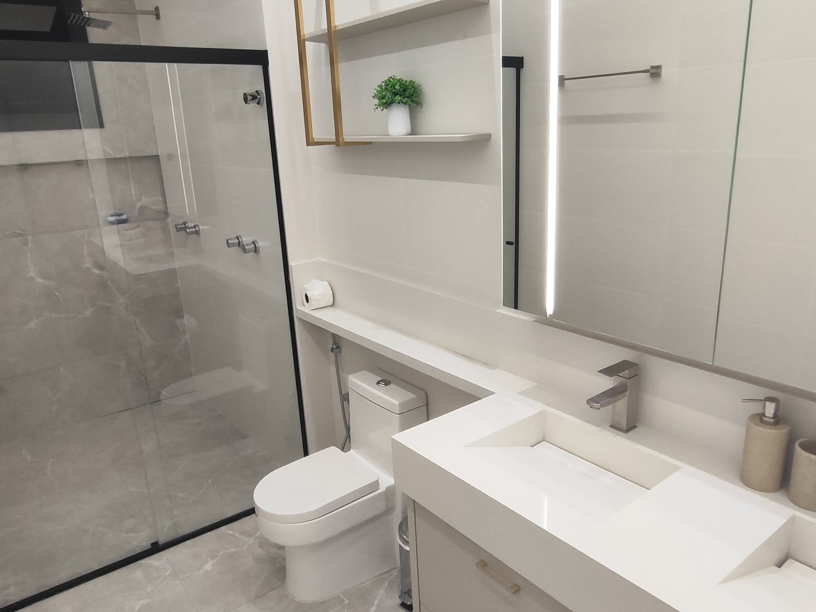 Banheiro en-suite com box de vidro preto e bancada de mármore