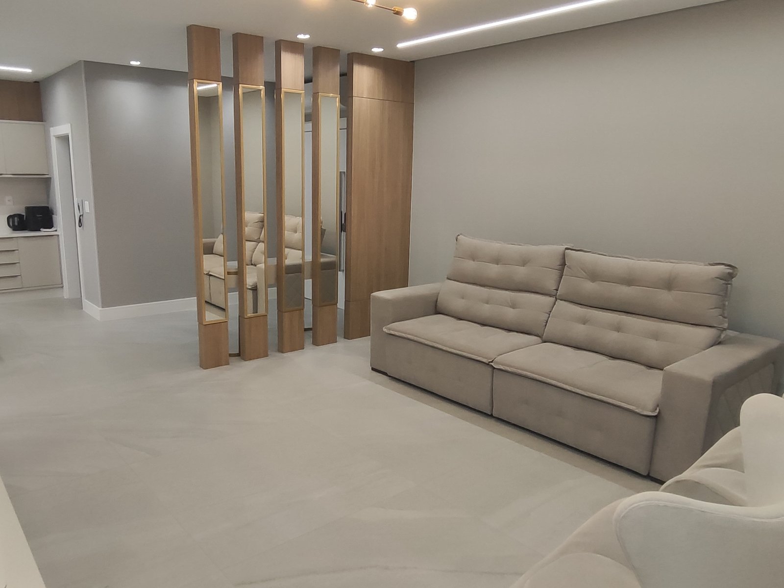 Sala de estar com sofá retrátil, vista para a divisória de madeira e espelho