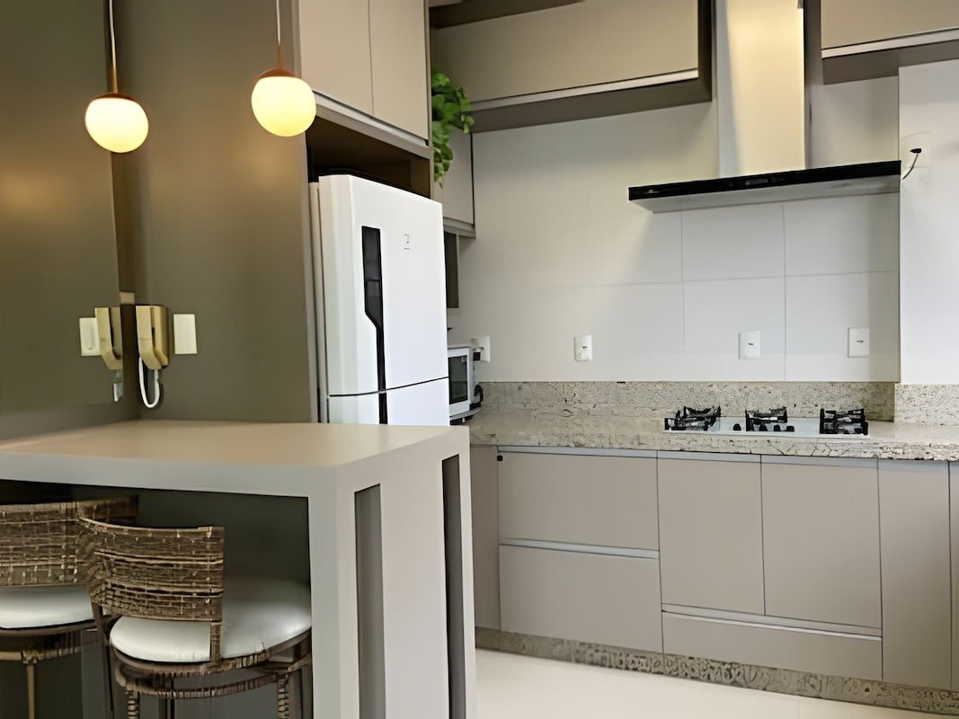 Cozinha americana com ilha, cooktop e geladeira