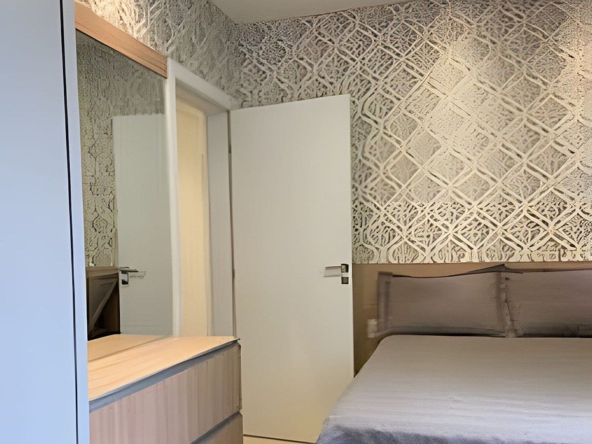 Quarto com papel de parede geométrico e cama de casal