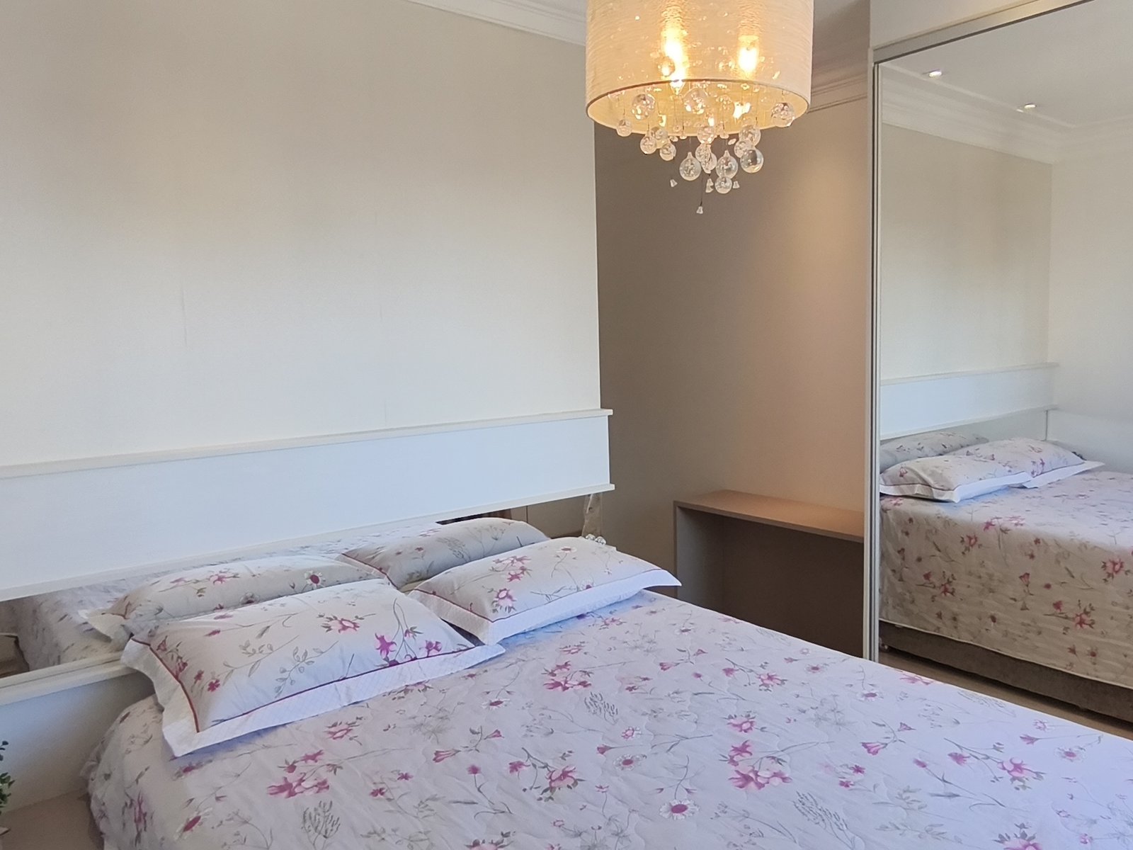Suíte com cama de casal e lustre de cristal