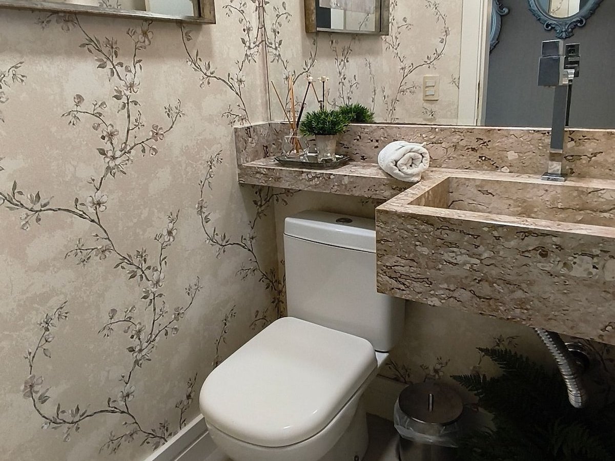 Lavabo com papel de parede floral e bancada de mármore