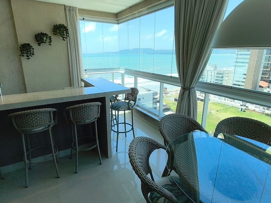 Bar da varanda gourmet com banquetas e vista pro mar