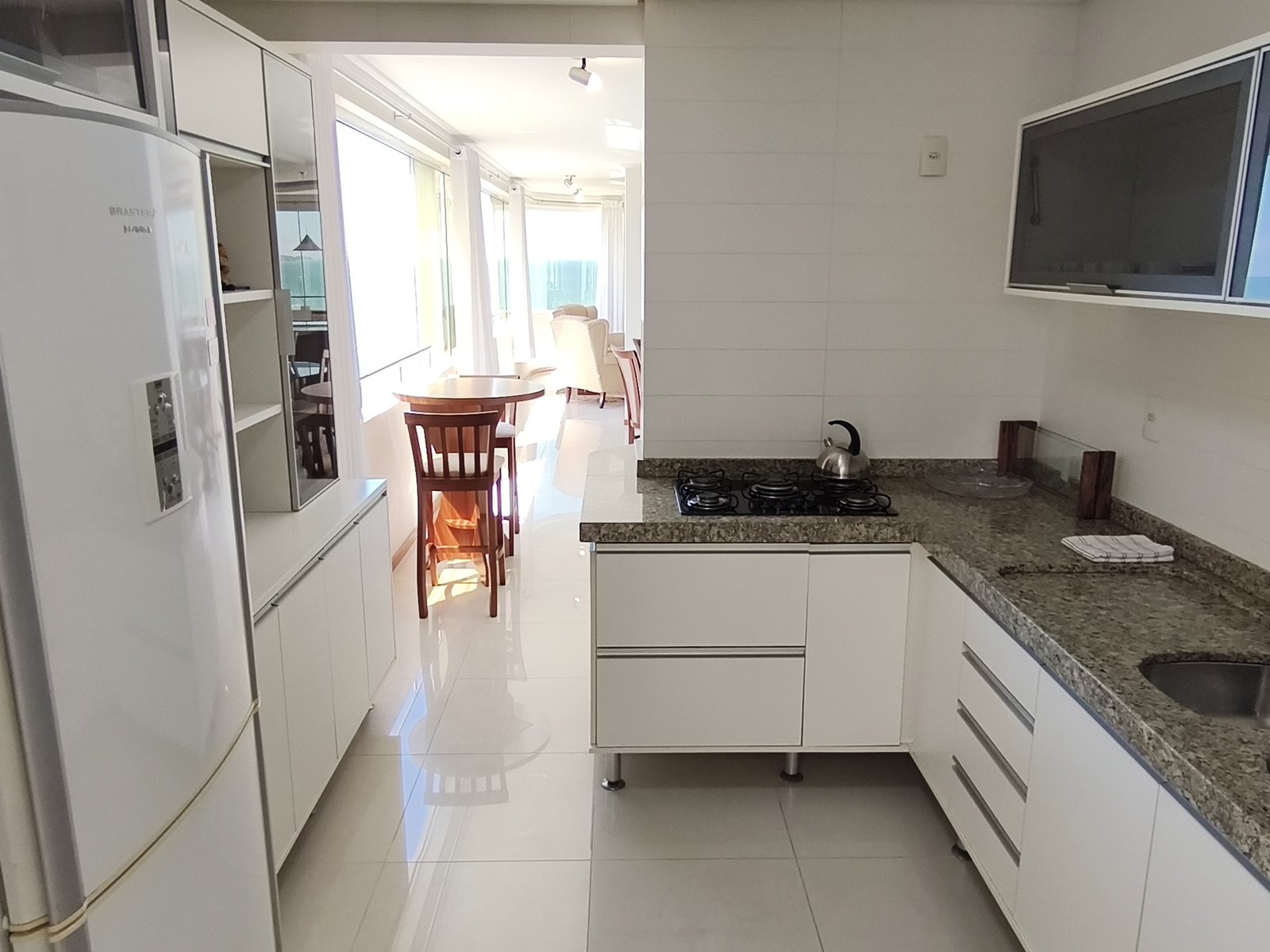 Cozinha com bancada de granito e vista para o mar ao fundo
