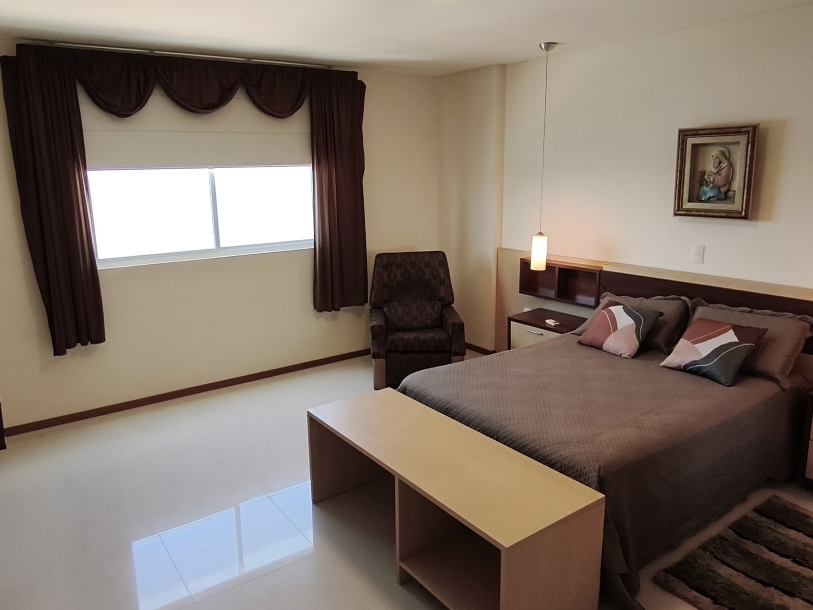 Suíte master ampla com cama de casal e poltrona