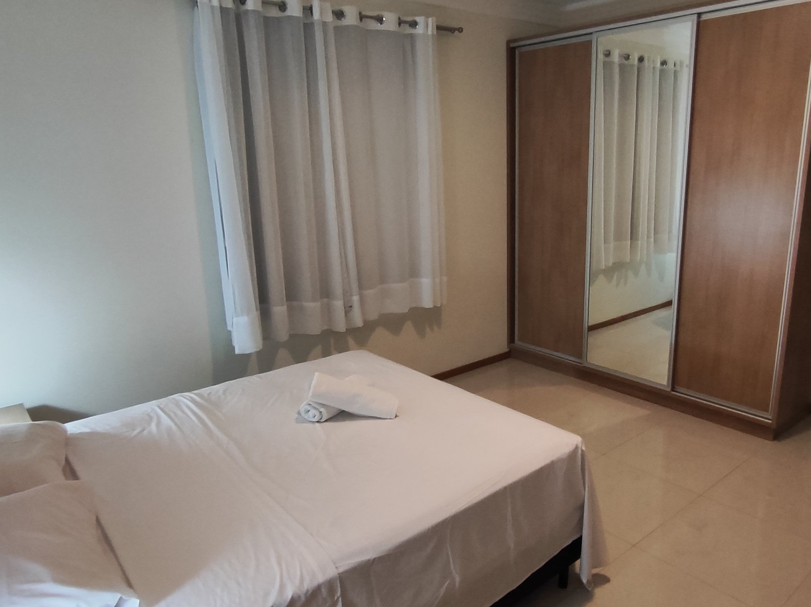 Quarto com cama de casal e closet espelhado