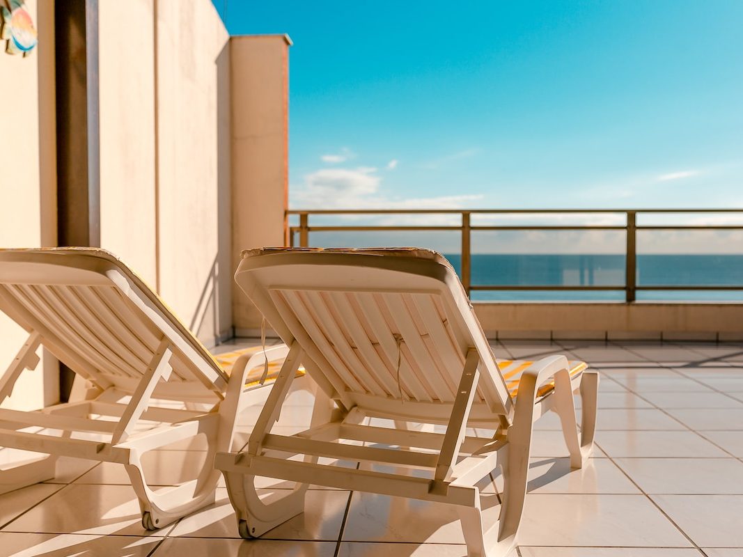 Duas espreguiçadeiras no terraço, viradas para o mar