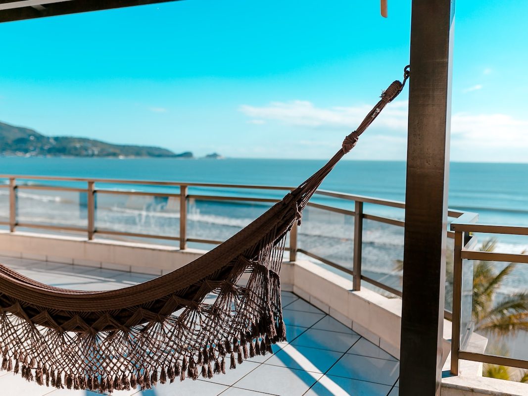 Rede armada na beira do terraço, com o mar aberto na frente
