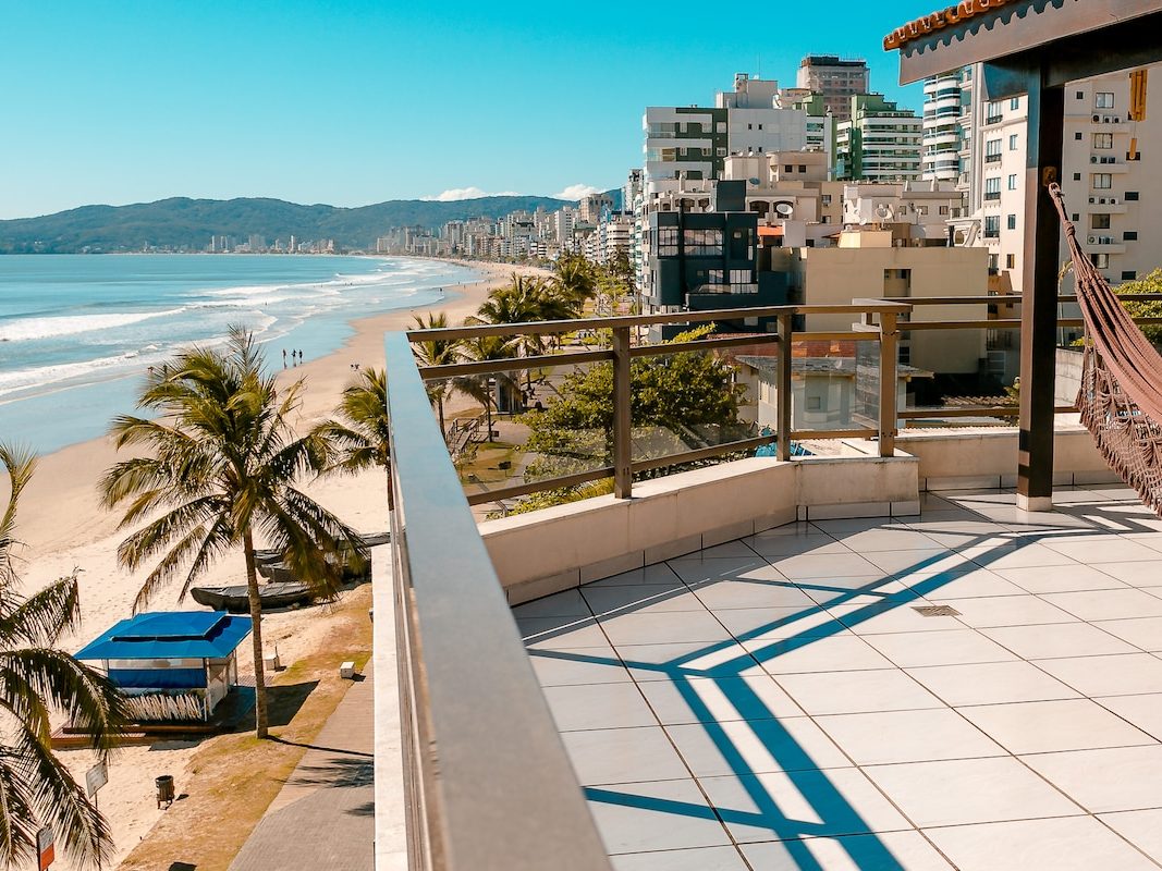 Terraço acompanhando a orla de Meia Praia, com a faixa de areia e os prédios ao fundo