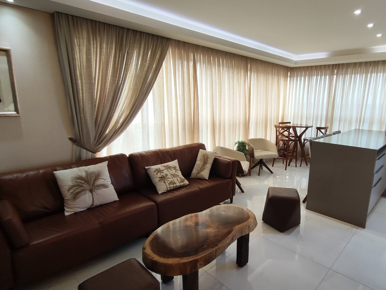 Sala de estar com sofá de couro e cortinas em toda a fachada