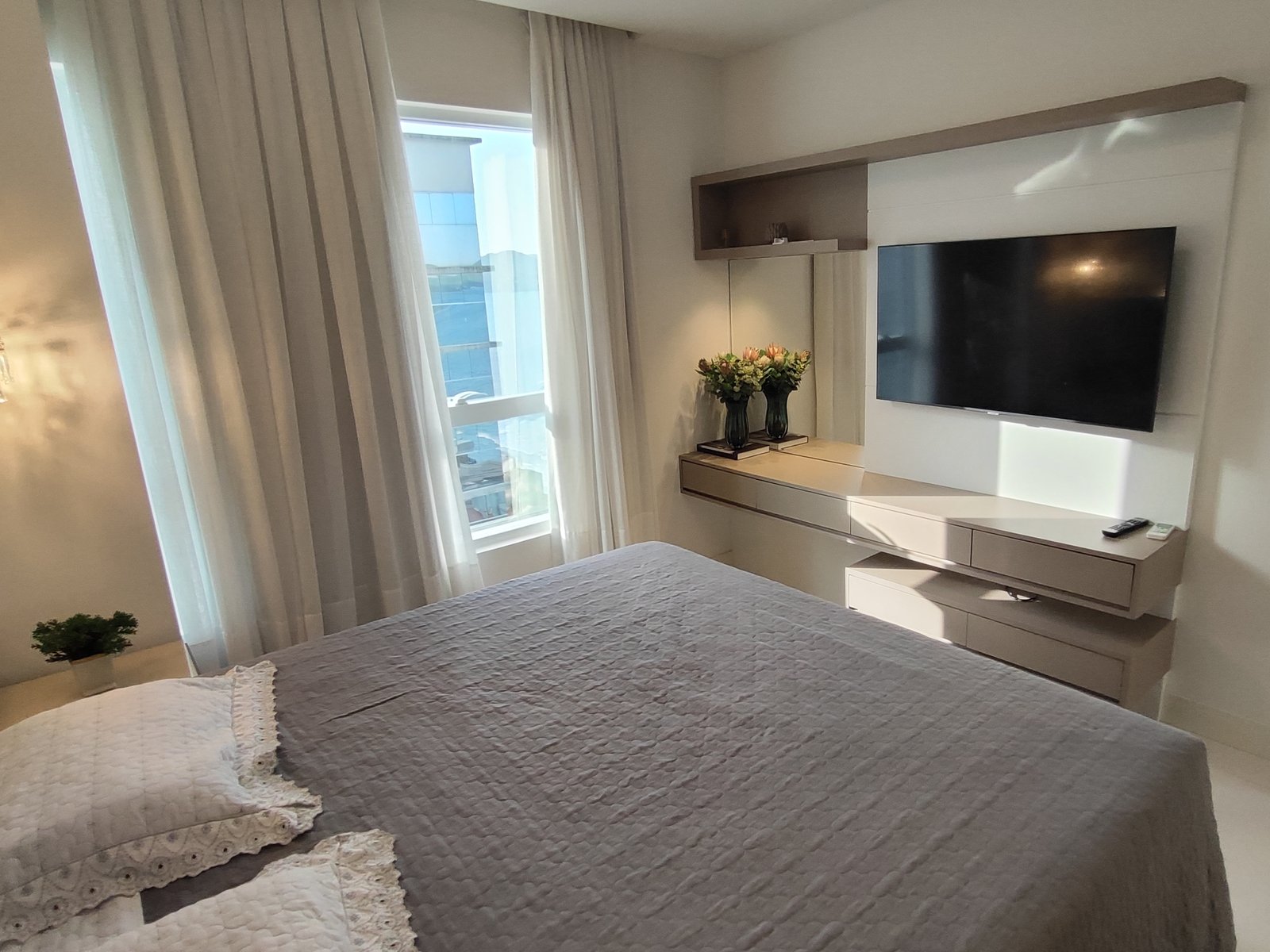 Suíte com cama de casal e TV de parede