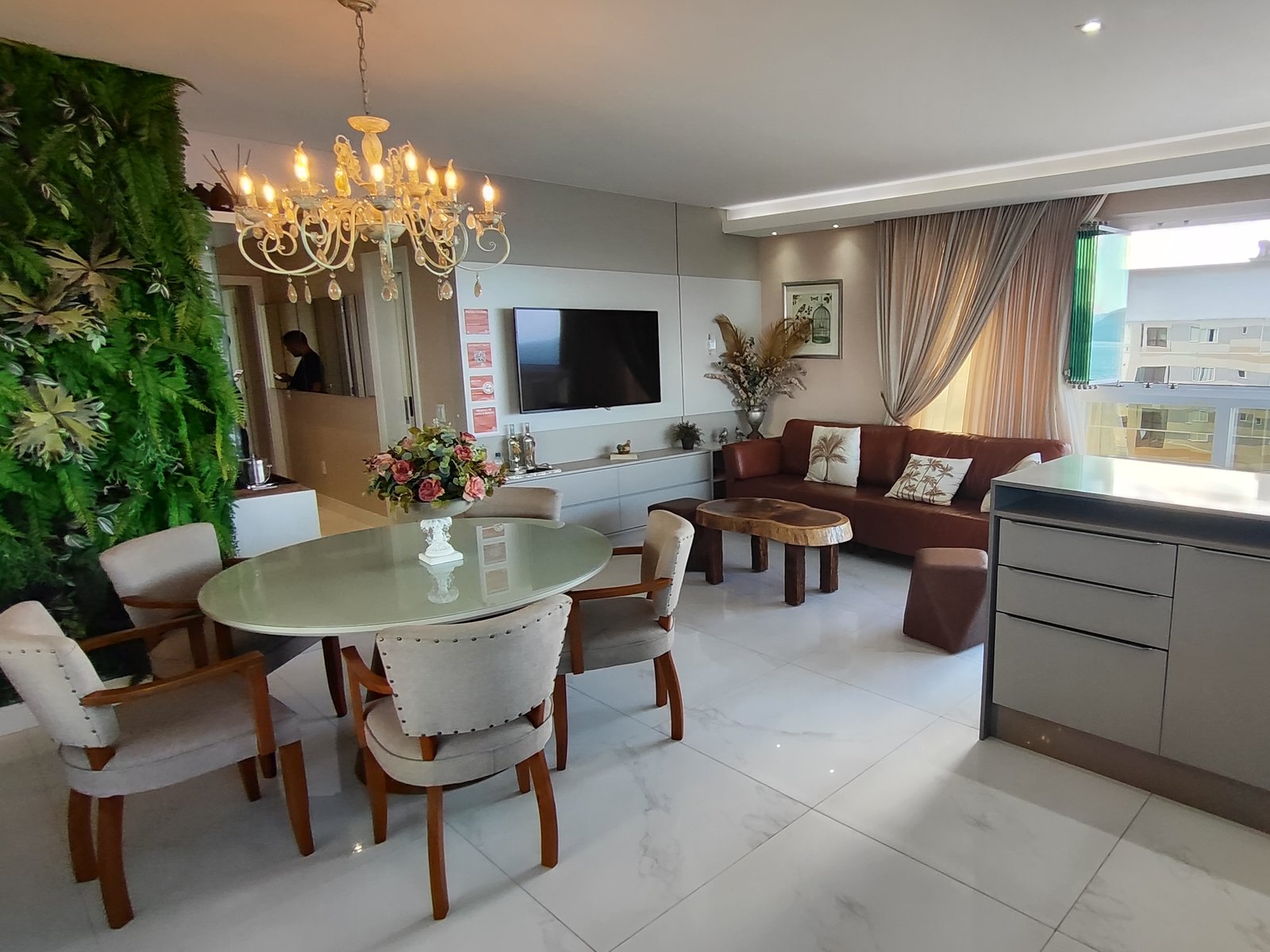 Sala de jantar com parede de jardim vertical e lustre de cristal