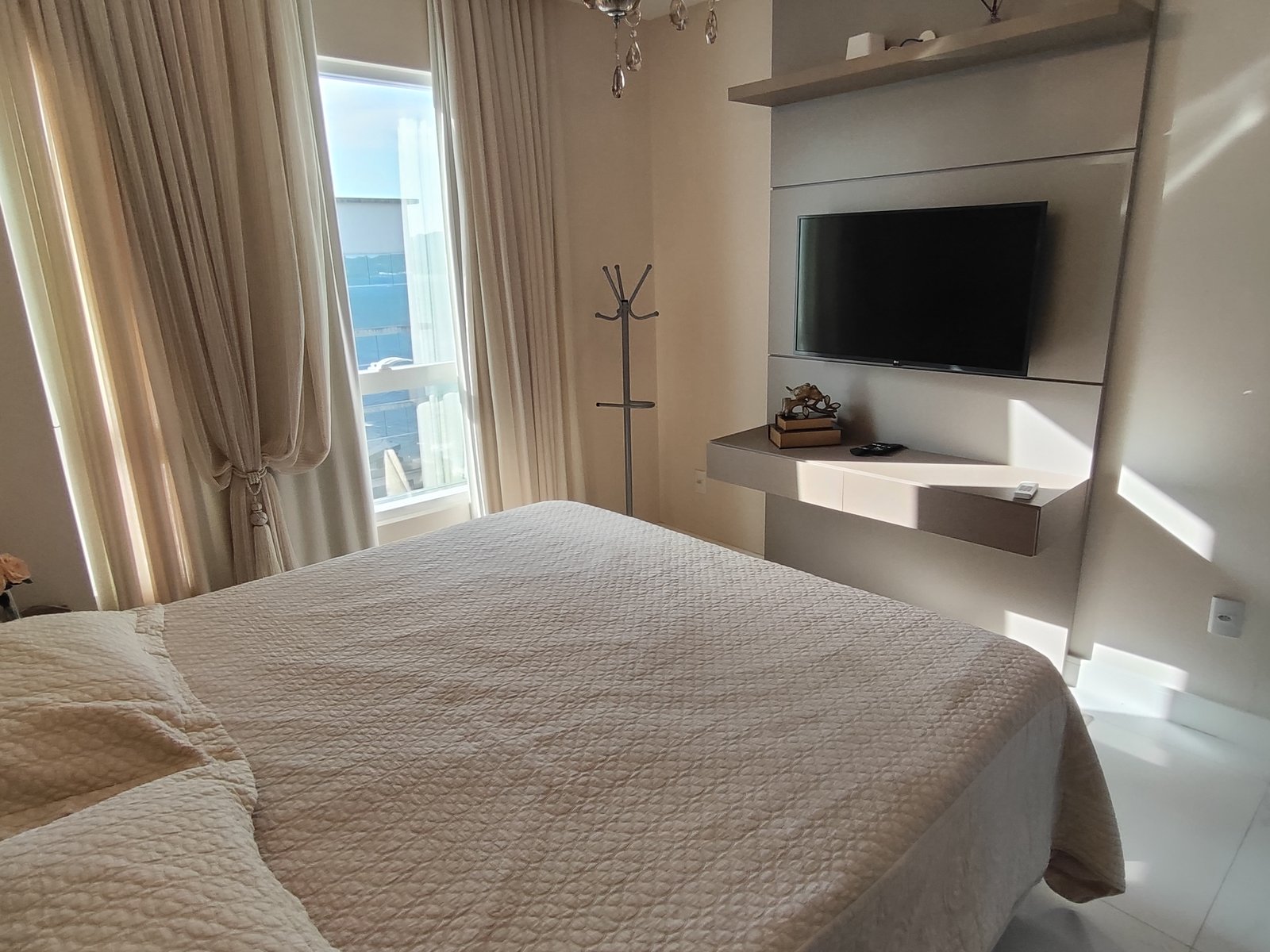 Suíte com cama de casal e TV de parede